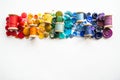 A lot of buttons and reels with colorful threads, laid out on a white background in the colors of the rainbow. Copy space