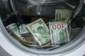 A lot of cash dollars is washed in the drum of a washing machine. Many banknotes are inside Washer. The concept of not legal money