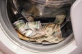 A lot of cash dollars is washed in the drum of a washing machine. Many banknotes are inside Washer. The concept of not legal money