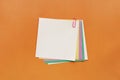 A lot of colored blank paper fastened pink paperclip on orange background Royalty Free Stock Photo