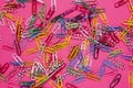 A lot of colored paper clips lie on a pink background Royalty Free Stock Photo