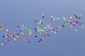 A lot of colorful balloons flying away in clear blue sky