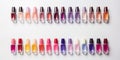 A lot of colorful bottles with nail polish lie on white background top view close up.Row of nail polishes for manicure Royalty Free Stock Photo