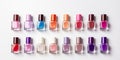 A lot of colorful bottles with nail polish lie on white background top view close up.Row of nail polishes for manicure Royalty Free Stock Photo