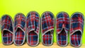 A lot of of colorful comfortable, cushioned, checkered disposable slippers leaned against yellow wall. Close-up