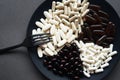 A lot of dietary supplements and tablets on a black plate next to the cutlery Royalty Free Stock Photo