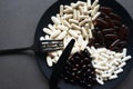 A lot of dietary supplements and tablets on a black plate next to the cutlery Royalty Free Stock Photo
