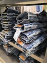 Lot of different color striped long sleeve,blue jeans shirts are neatly stacked in a row on the store shelves