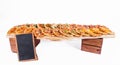 A lot of different pizzas with different tastes on a wooden board on a white background. Black slate for writing menu stands next Royalty Free Stock Photo