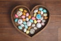 A lot of easter eggs and cake in wooden box heart form on wooden background. Spring and Easter holiday. Minimalistic Royalty Free Stock Photo