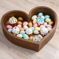 A lot of easter eggs and cake in wooden box heart form on wooden background. Spring and Easter holiday. Minimalistic Royalty Free Stock Photo