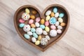 A lot of easter eggs and cake in wooden box heart form on wooden background. Spring and Easter holiday. Minimalistic Royalty Free Stock Photo
