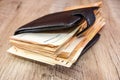 A lot of euro banknotes in a black men`s wallet on a wooden background. Thick wallet with money. 50 euros in a wallet