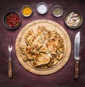 Lot of fried appetizing chicken steaks with herbs hot pepper and garlic with a fork knife on a round cutting board on rustic w