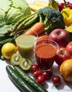 A lot of fruits and vegetables on a white background with a glass of green smoothie and vegetable juice