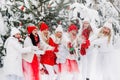 A lot of girls open a bottle of champagne violently in the winter new year`s forest.Girls in red and white clothes with new year Royalty Free Stock Photo