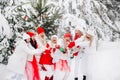 A lot of girls open a bottle of champagne violently in the winter new year`s forest.Girls in red and white clothes with new year Royalty Free Stock Photo