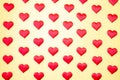 A lot of identical red silk hearts lying staggered on a yellow background. Symbol of love, tenderness and passion Royalty Free Stock Photo