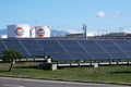 A lot of industrial solar panels for the production of electricity on the background of the fuel industry tank farm