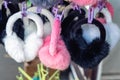 Lot of many multicolored bright fluffy warm winter fur earphones and gloves hanged on rack at store display for sale. Cute cold Royalty Free Stock Photo