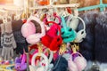 Lot of many multicolored bright fluffy warm winter fur earphones and gloves hanged on rack at store display for sale. Cute cold Royalty Free Stock Photo