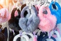 Lot of many multicolored bright fluffy warm winter fur earphones and gloves hanged on rack at store display for sale. Cute cold Royalty Free Stock Photo