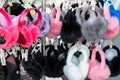 Lot of many multicolored bright fluffy warm winter fur earphones and gloves hanged on rack at store display for sale. Cute cold Royalty Free Stock Photo