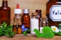 A lot of medical glas vials on table, filled with globulis and pills. Decoratet with leaves and flowers.