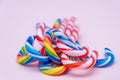 Lot of multi-colored candy canes on a pink background, copy space
