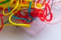 A lot of multi-colored mixed thread for embroidery on a white fabric, macro photo