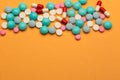 Lot of multicolored pills and tablets on orange background with free space for text or prescription Royalty Free Stock Photo