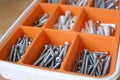 A lot of nails and screws in an orange box, tools for repair, building Royalty Free Stock Photo