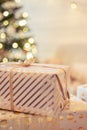 A lot of packing handmade gift boxes lying on the table near Christmas tree in the midst of golden lights, glowing garland, candle