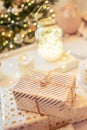 A lot of packing handmade gift boxes lying on the table near Christmas tree in the midst of golden lights, glowing garland, candle