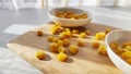 Lot of pieces of canned yellow corn on plate which is on wooden bamboo cutting board on white background. The concept of