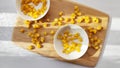 Lot of pieces of canned yellow corn on plate which is on wooden bamboo cutting board on white background. The concept of