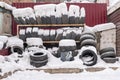 A pile of worn, used car tires lie in the snow in winter