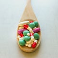 A lot of pills and vitamins in a wooden spoon on a on light background. Royalty Free Stock Photo