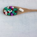 A lot of pills and vitamins in a wooden spoon on a on light background. Royalty Free Stock Photo