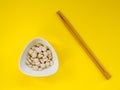 A lot of pills in a white bowl and wooden chopsticks on a yellow background. The concept of overuse of drugs. Flat lay