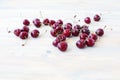 A lot of red berries of sweet cherry scattered on light wooden table close up, bunch of ripe cherry berries on white background