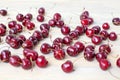 A lot of red berries of sweet cherry scattered on light wooden table close up, bunch of ripe cherry berries on white background Royalty Free Stock Photo