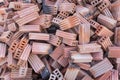 A lot of red bricks are stacked on the floor. Piles of red construction bricks scattered on the ground