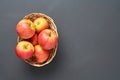 Lot of red fresh whole ripe apples full of vitamins lies in wooden wicker basket and old dark scratched concrete table on kitchen