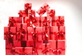 A lot of red gift boxes tied with ribbons on a white wall background. A bunch of gifts in bright festive packaging. Red boxes on a