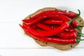 A lot of red pepers chilli lies on an oval Brown Board, which stands on a white wood table Royalty Free Stock Photo