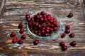 A lot of ripe red cherries on twigs lie in a glass plate on a dark blue wooden table with a striped texture Royalty Free Stock Photo