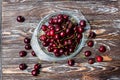 A lot of ripe red cherries on twigs lie in a glass plate on a dark blue wooden table Royalty Free Stock Photo