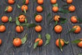 Lot of ripe round orange Mandarin in smooth few rows on dark black wooden background