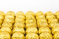 A lot of shiny golden chocolate wrapper in line on white background